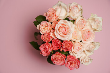 Beautiful white, red, tabby tea rose flowers in a vase, photographed from above on the pink table. Spring flowers. Wedding mothers day and valentines day background. Selective small depth of field.