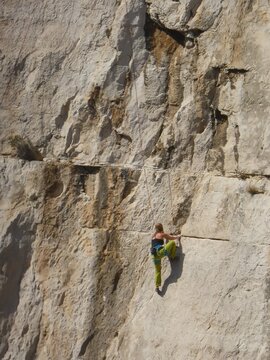 Femme pratiquant le sport de l'escalade sur une paroi rocheuse dans la nature, sur les falaises abruptes des calanques de Marseille (France)
