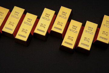Gold bars next to each other on a black background. Shiny precious metal for investment or as a reserve. Place for text.