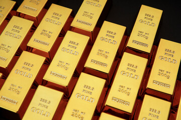 Gold bars next to each other on a black background. Shiny precious metal for investment or as a reserve. Place for text.
