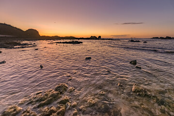 Naklejka premium Sunset seen from a rocky beach
