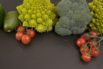 Healthy vegetarian food, fresh green food, green vegetable, romanesco broccoli, pepper, zucchini and avocado, free space in your text, on a black table