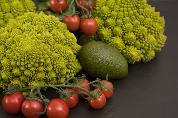Healthy vegetarian food, fresh green food, green vegetable, romanesco broccoli, pepper, zucchini and avocado, free space in your text, on a black table