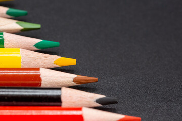 Close-up of colored pencils with dark background and some copy space for free text, ideal for school and arts