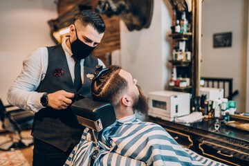 Young good looking hipster man visiting barber shop. Trendy and stylish beard styling and cut.