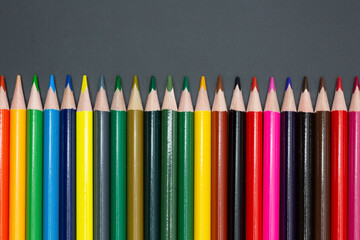 large set of crayons lined up in different colors with dark background for school and arts with copy space for free text