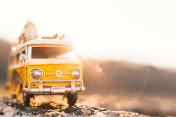 Small hippie yellow van toy on the road. Vacation, traveling concept