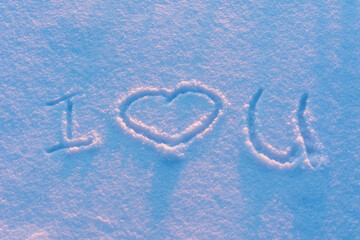 Abbreviated inscription on the snow I love you in the light of the evening winter sun
