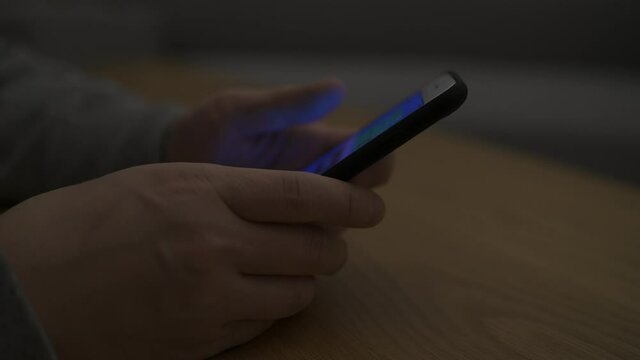 暗い部屋でスマートフォンを操作している男性