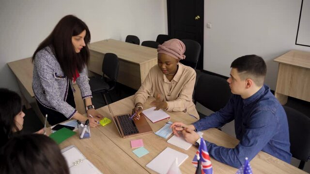 Teamwork. Working in multiethnic group of students. teacher study foreign languages together in class. Studing with laptop. Black handsome girl student study with white people together
