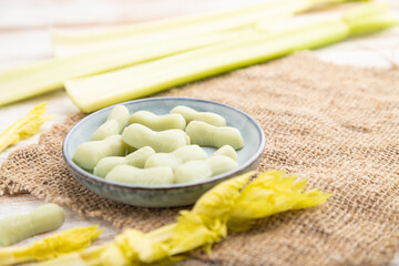 Jelly celery candies on white wooden background. side view, selective focus.