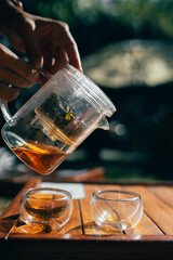 Pouring black tea, female hand holding a teapot