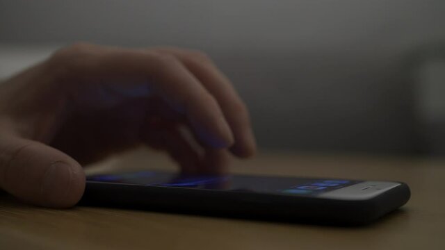 暗い部屋でスマートフォンを操作している男性
