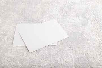 White paper business card, mockup on gray concrete background. Blank, side view