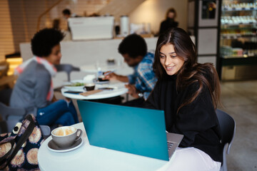 Fototapeta premium Portrait of female student using net-book while sitting in cafe