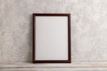 Brown wooden frame mockup on gray concrete background. Blank, vertical orientation, copy space.