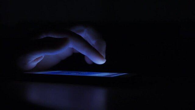 暗い部屋でスマートフォンを操作している男性