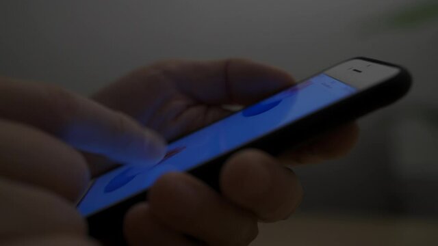 暗い部屋でスマートフォンを操作している男性