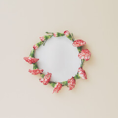 Obraz premium Wreath made of carnation on pastel background. Festive floral frame with space for text.