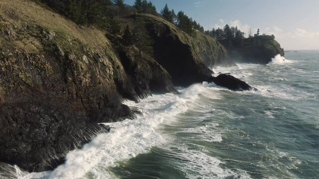 Stunning Coastal Aerial of Waves Crashing Cliffs Slow Motion Below Lighthouse
