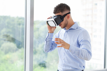 Young man wearing virtual reality goggles in modern coworking studio.
