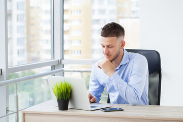 Portrait of young man sitting at his desk in the office