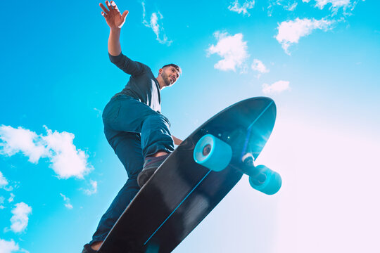 Skateboarder in action. Man riding on a skateboard outdoors on sunny summer day. Blue sky background.