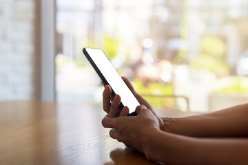 Close up hands of beautiful young woman holding mobile, smart phone sitting in cafe. Soft focus hands of women holding and use cell phone in coffee shop. Tech Technology and lifestyle concept.