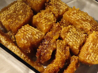 Organic honey from various flowers in honeycomb with wax caps on, in rectangle glass tray. Close up, selective focus
