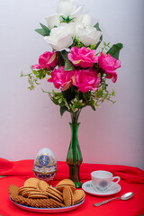breakfast with chocolate cookies, cup of coffee and vase with pink flowers.
