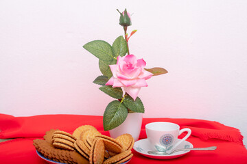 breakfast with chocolate cookies, cup of coffee and vase with pink flowers.
