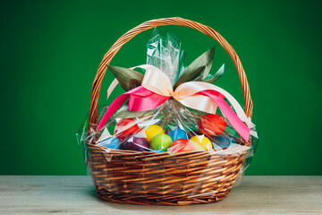 Easter gift basket with multicolor eggs, green background