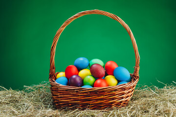 Easter basket with multicolor eggs, green background