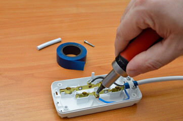 Master repairs an extension cord with a screwdriver