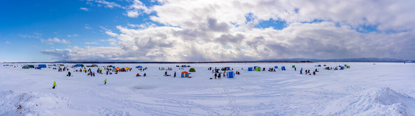 Sakhalin, Russia - 02.21.2021: People catch fish during traditional ice fishing competition on the Naiba river.Panorama