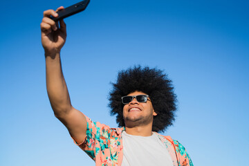 Latin man taking a selfie with phone outdoors.