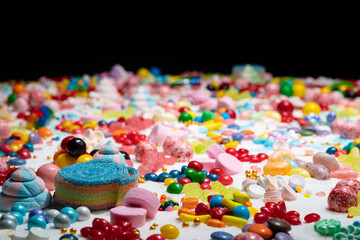 Fototapeta na wymiar Random candy, shallow depth of field. Mixed colorful lollipops and gums, unicorn poop marshmallows explosion. Variety flavoured confetti of sweets, sugar and cake icing, caramel feast celebration