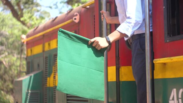 trainmaster holding green signal flag on Matheran