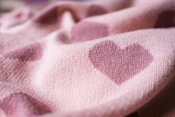 Dark pink heart shape on a scarf with a light pink silk background. Winter valentine's day and love concept