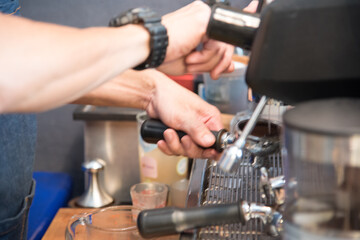 Coffee barista make espresso shot from coffee maker hot cup. Cappuccino with milk in italian coffee shop cafe. Close up hands of barista use machine make brown latte art for customer cafeteria.