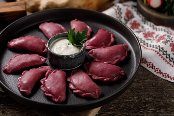 Delicious traditional Russian dumplings, handmade dough painted with beets. Still life on a wooden board. Close-up.