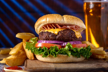 hamburger with beef meat prosciutto cheese onion lettuce tomato and fries on wood table with colors background