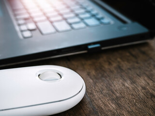 White wireless mouse on wooden desk.