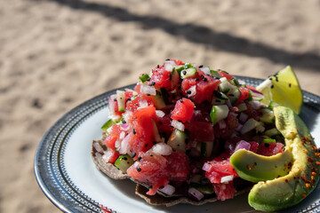 Tuna Ceviche Tostada served with avocado and lime on the beach in Mexico
