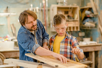 father teaching his son carpentry, varnishing wooden parts