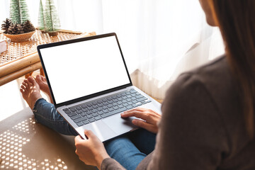 Mockup image of a woman working and typing on laptop computer with blank white screen at home