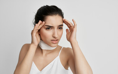 brunette with a bandaged neck holding her head health problems