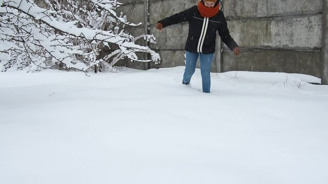 woman walks through fresh snow and leaves deep footprints. front view slow motion