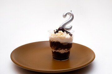 Birthday trifle cake with candle labeled number 2 on plate. portioned mini cake