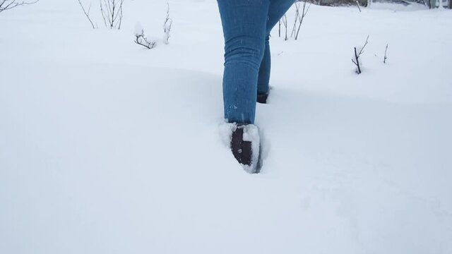 Legs walking on snow with footprints. rear view. camera follows the legs